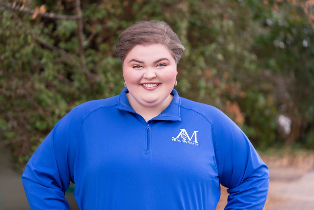 A person in a blue polo shirt with an AM logo stands outdoors against a natural background.
