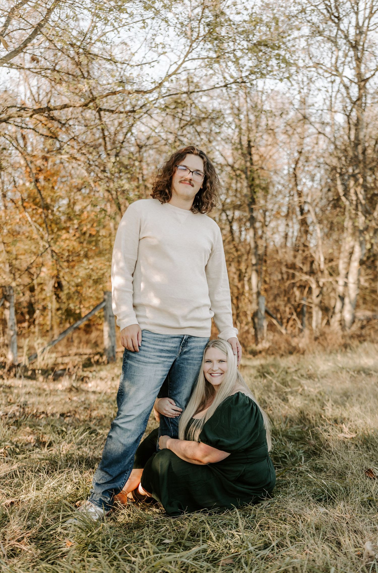 Couple relaxing on grass during autumn outdoor photoshoot.