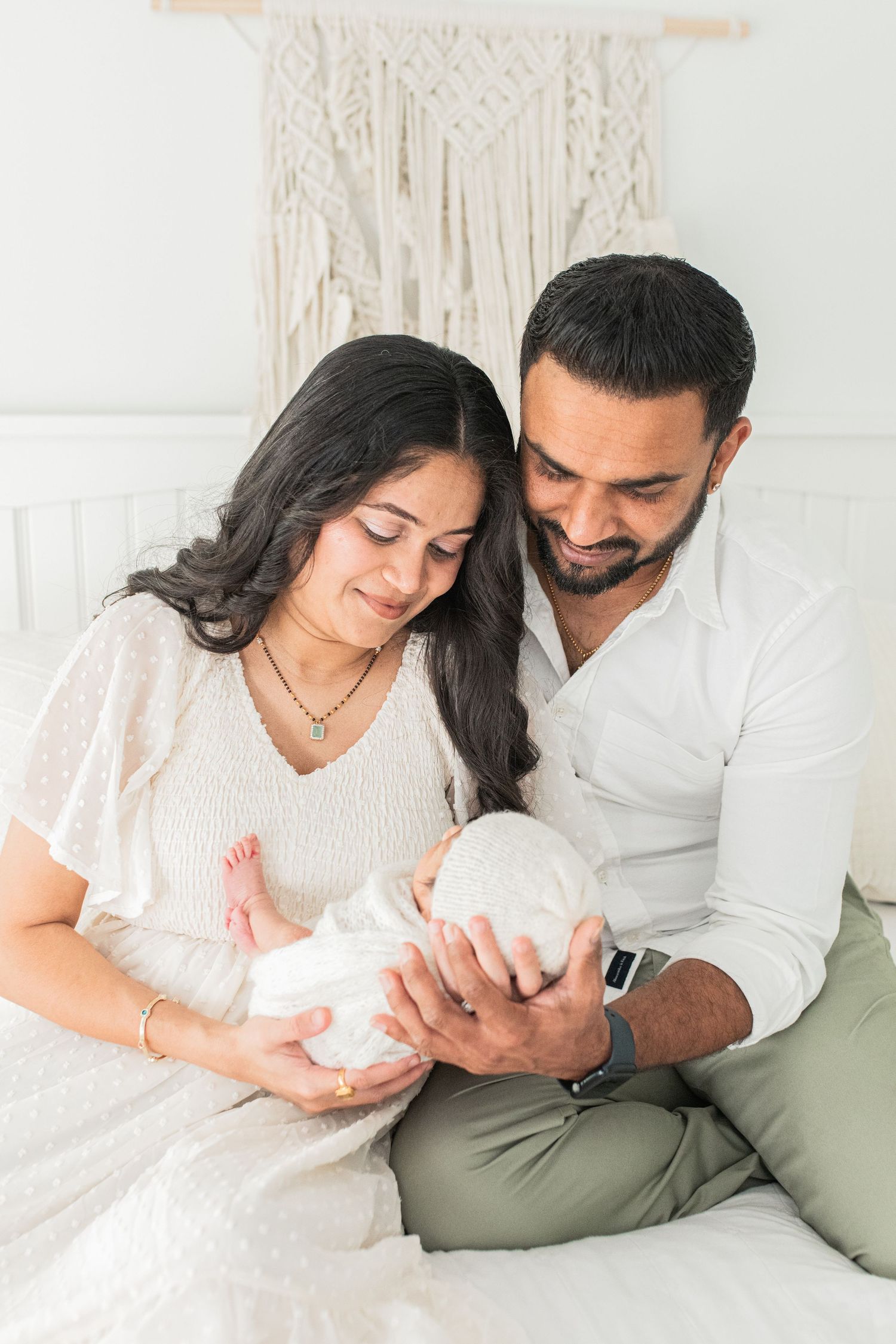 Mom and dad holding their newborn baby, filled with happiness and pride, captured during a professional newborn photography session.