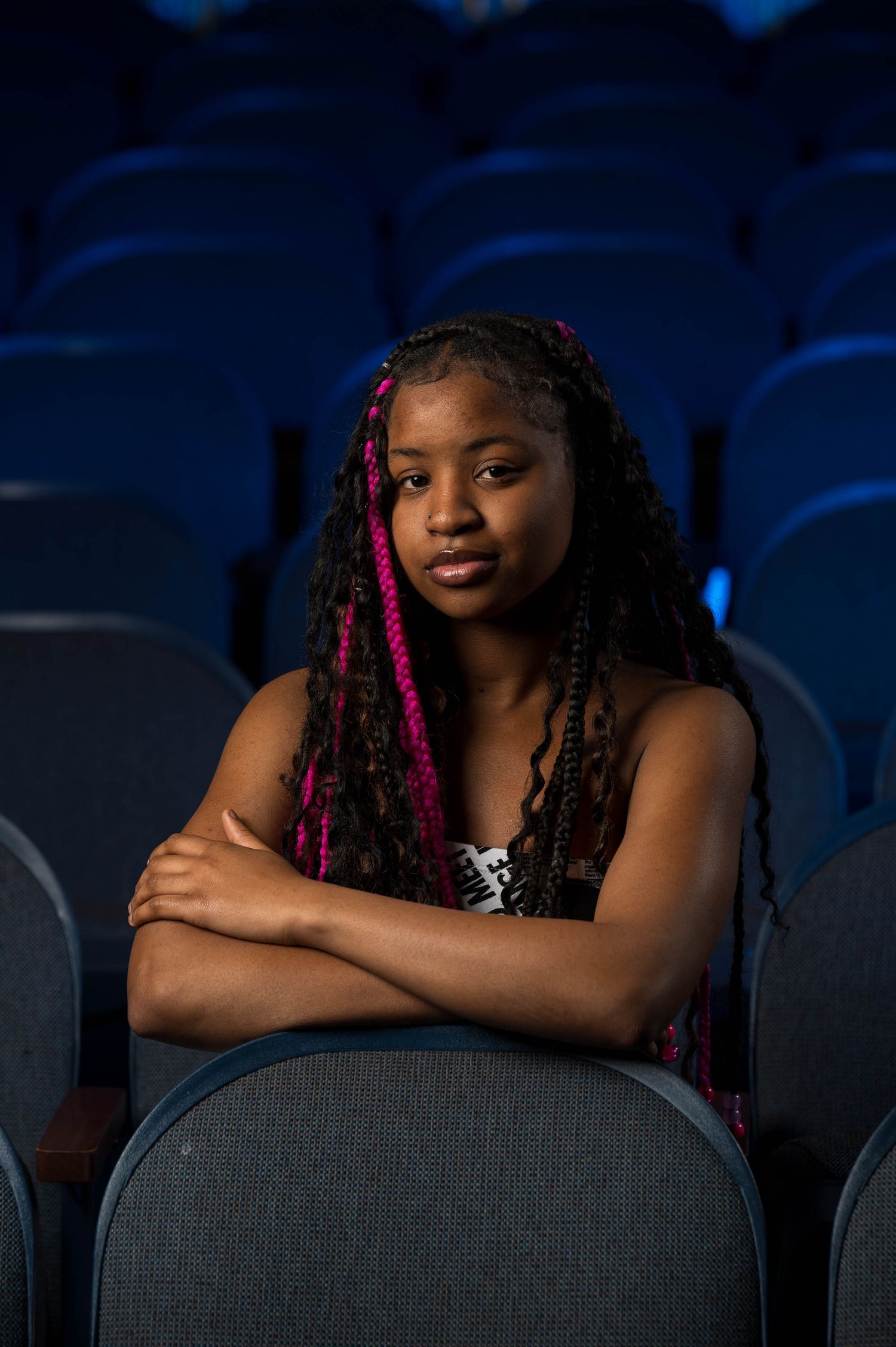 Young African American girl actor portrait posing in Lockport, NY theatre with arms crossed and blue background light
