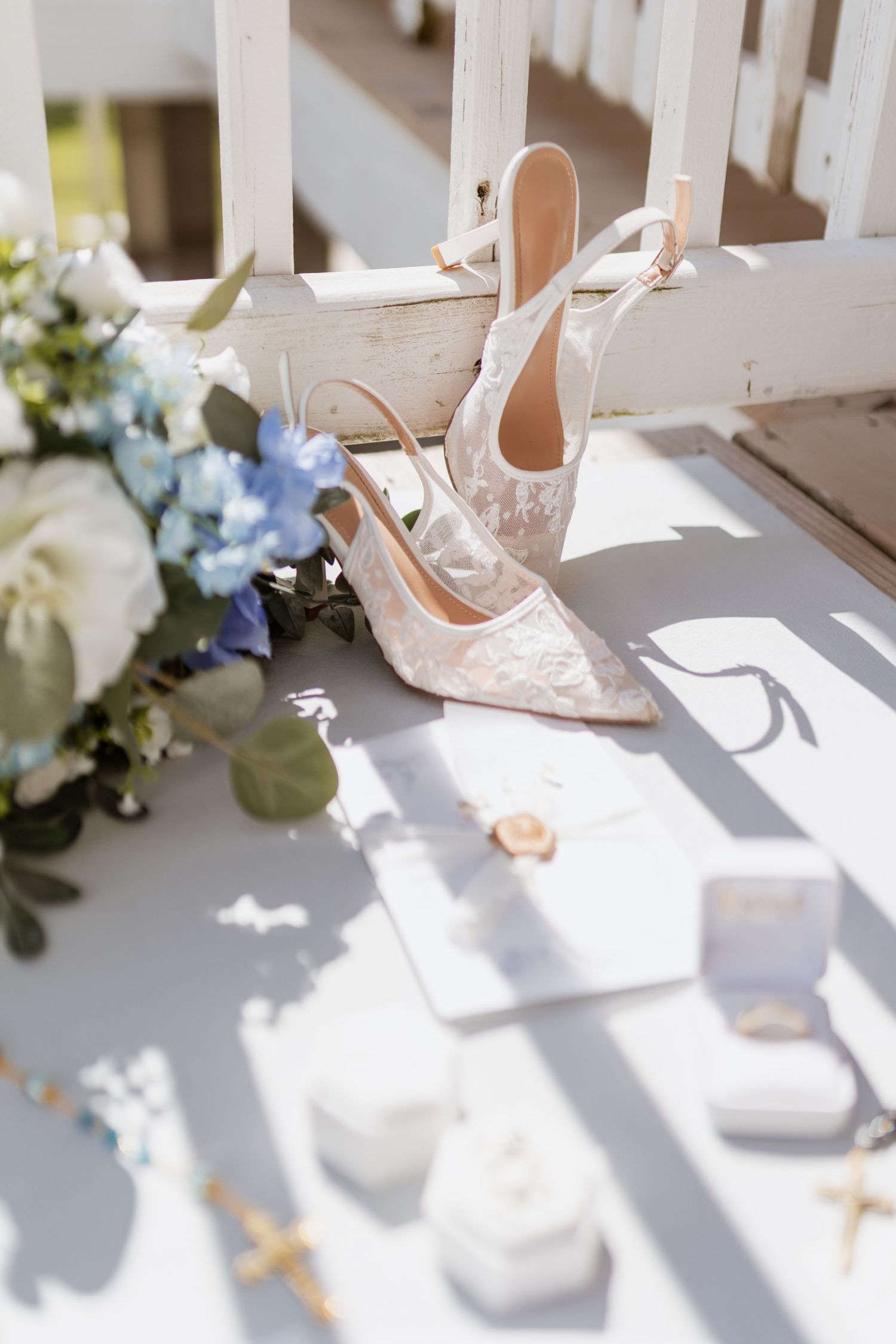 A black and white photograph of elegant white bridal sandals and hydrangea flowers on a wicker basket.