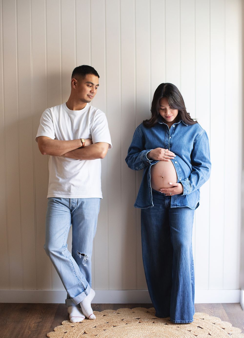 Couple in a maternity photoshoot in South East London. Man in white tee and jeans, pregnant woman in denim outfit cradling her baby bump.