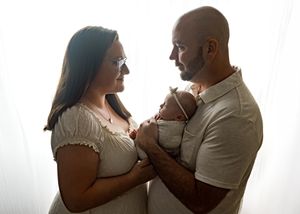 Couple in white clothing sharing an intimate moment together against bright backlit background.