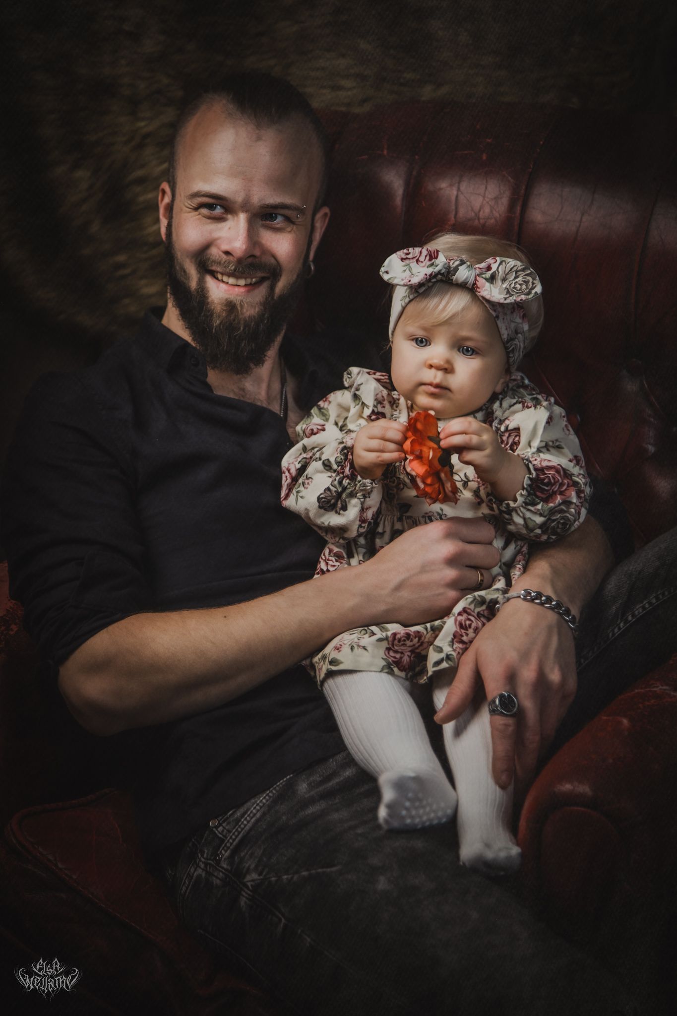 Loving portrait of parent and infant in coordinated outfits seated on leather chair.