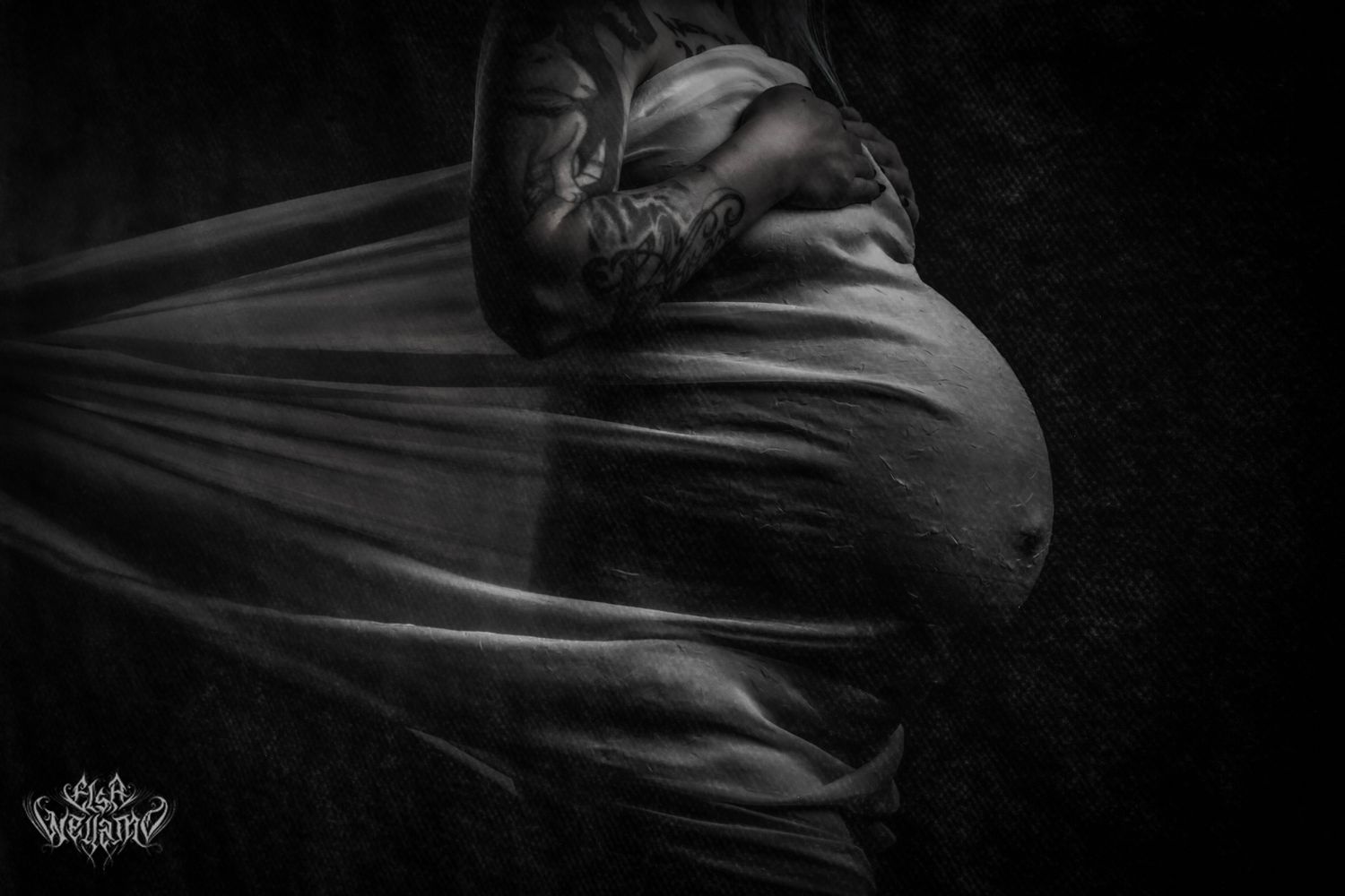 Dark artistic black and white photo showing movement with flowing fabric creating dramatic shadows and silhouettes.