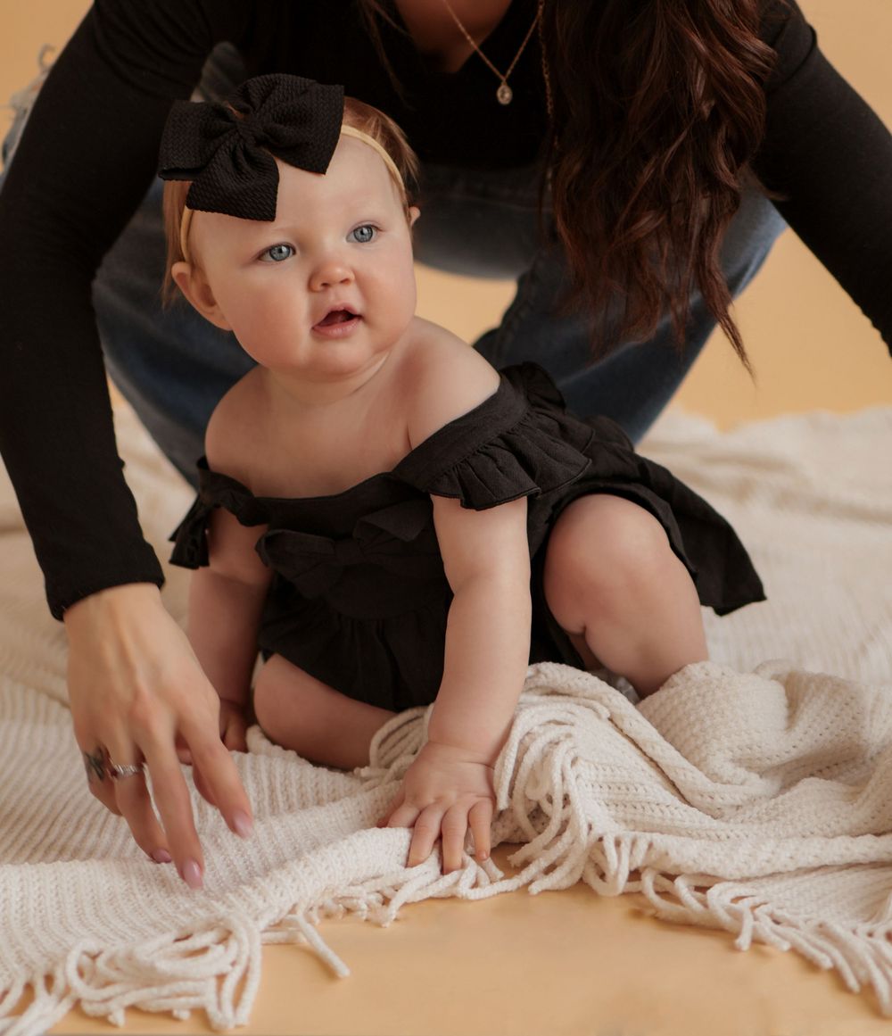Close-up shot of a baby playing on a white textured blanket.