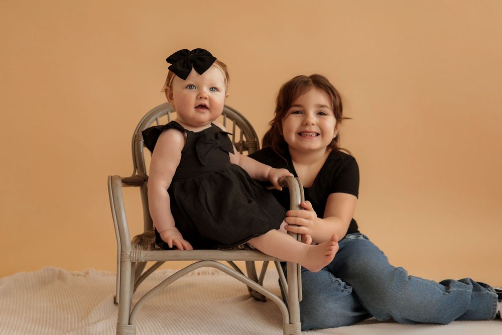 Family photo session with mother and baby against warm beige background.