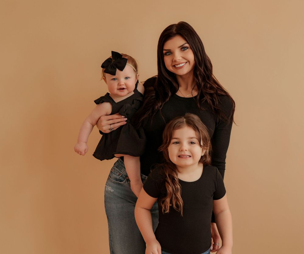 Family portrait session featuring casual outfits against beige backdrop.