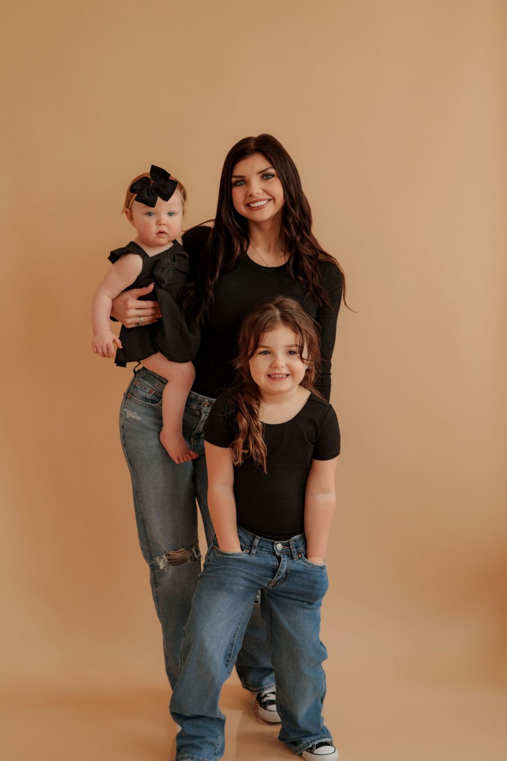 A playful photo series showing a parent and child in matching black shirts and jeans against a warm brown backdrop.