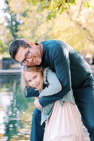 A romantic couple embraces and shares tender moments by a tranquil pond in an autumn setting.