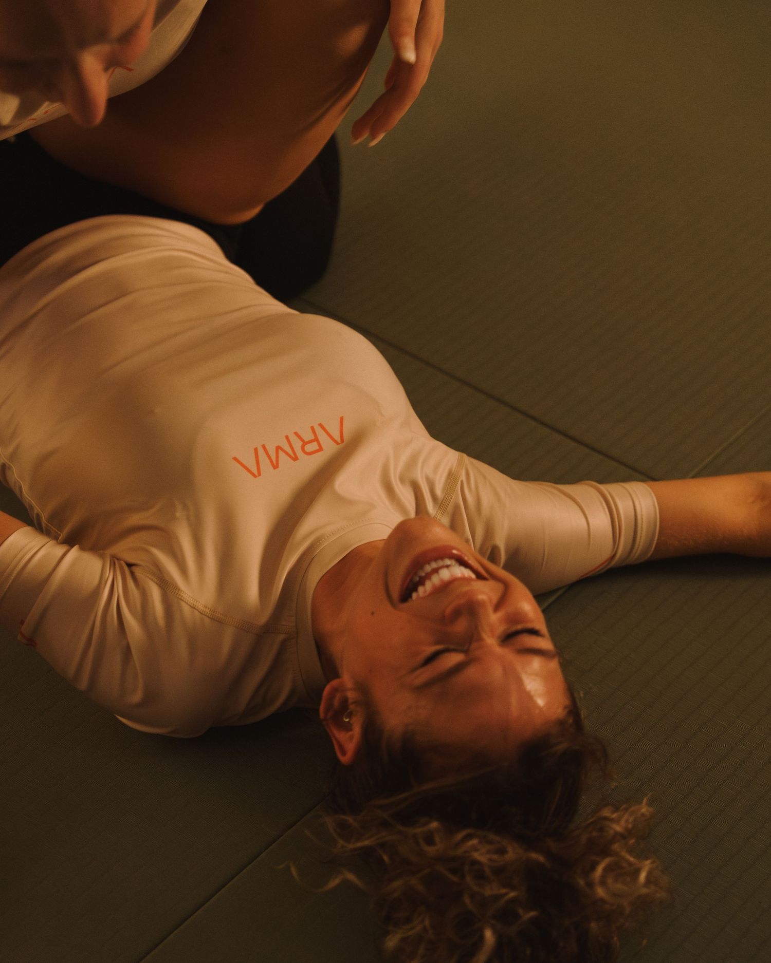 A person lies on a dark floor wearing a white shirt in a dimly lit setting, creating a moody atmospheric scene.