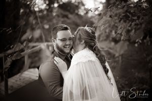 A couple shares an intimate moment exchanging vowels on a rustic wedding lush green forest foliage.