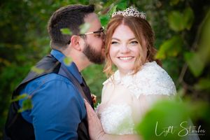 A couple shares an intimate moment exchanging vowels on a garden wedding surrounded by lush green forest foliage.
