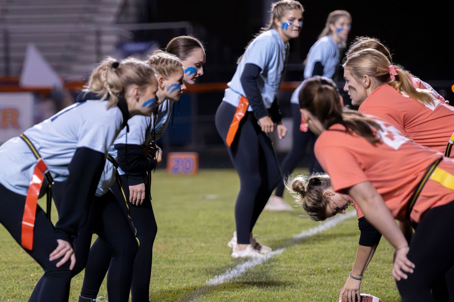 Flag football players line up during a nighttime game.