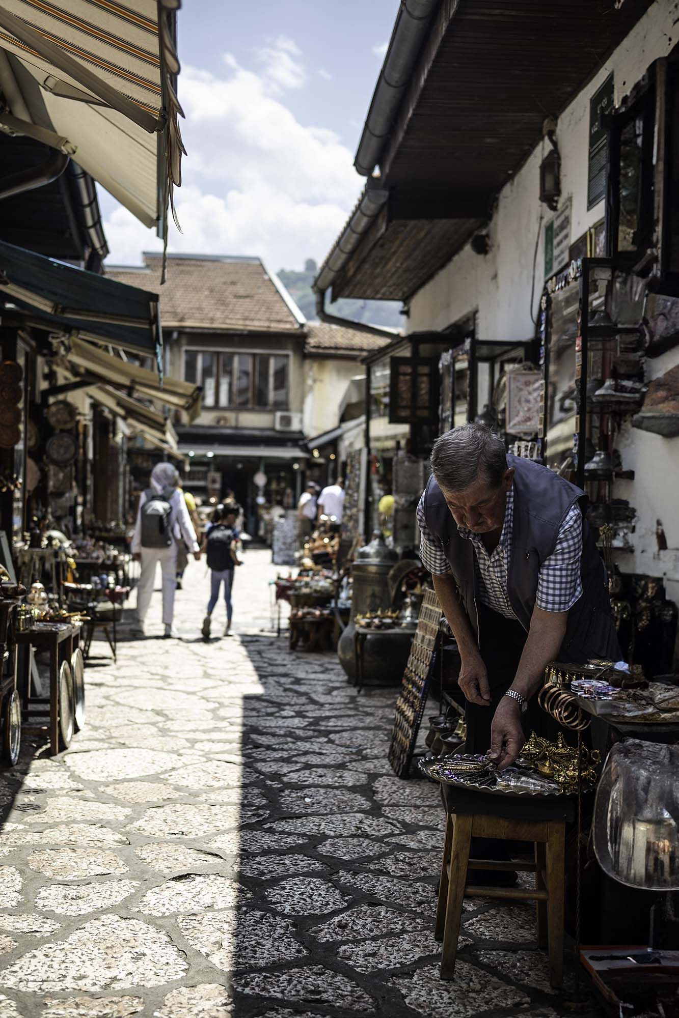 Traditional cobblestone street lined with small shops and market stalls in a historic district.