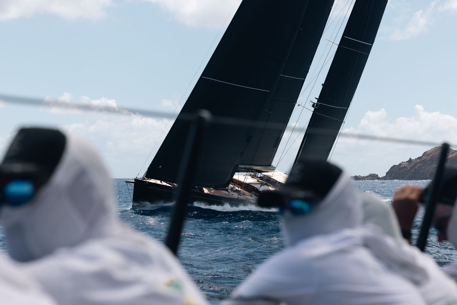 Close-up shot of sailing yacht deck equipment with blurred ocean horizon in background.
