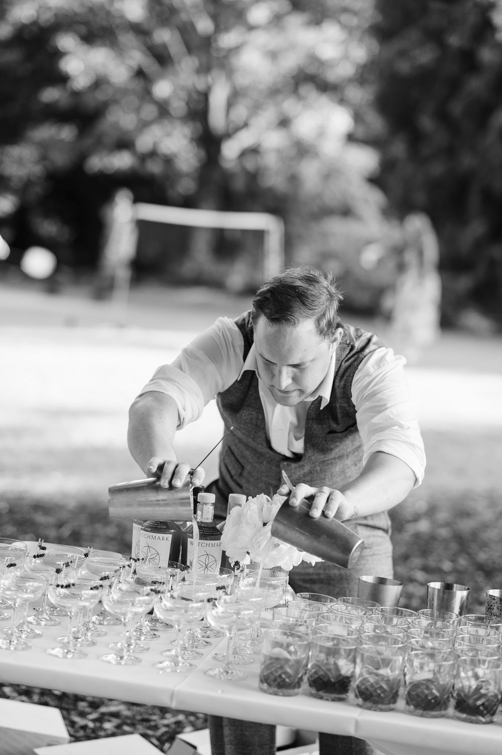 A sequence of black and white photos showing someone carefully arranging glass jars in a line outdoors.