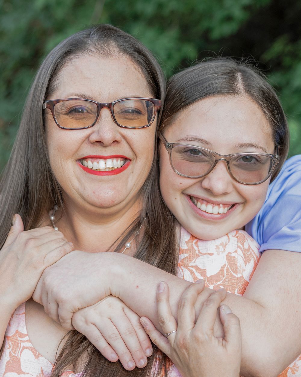 Close up portrait of two people embracing and smiling at camera.