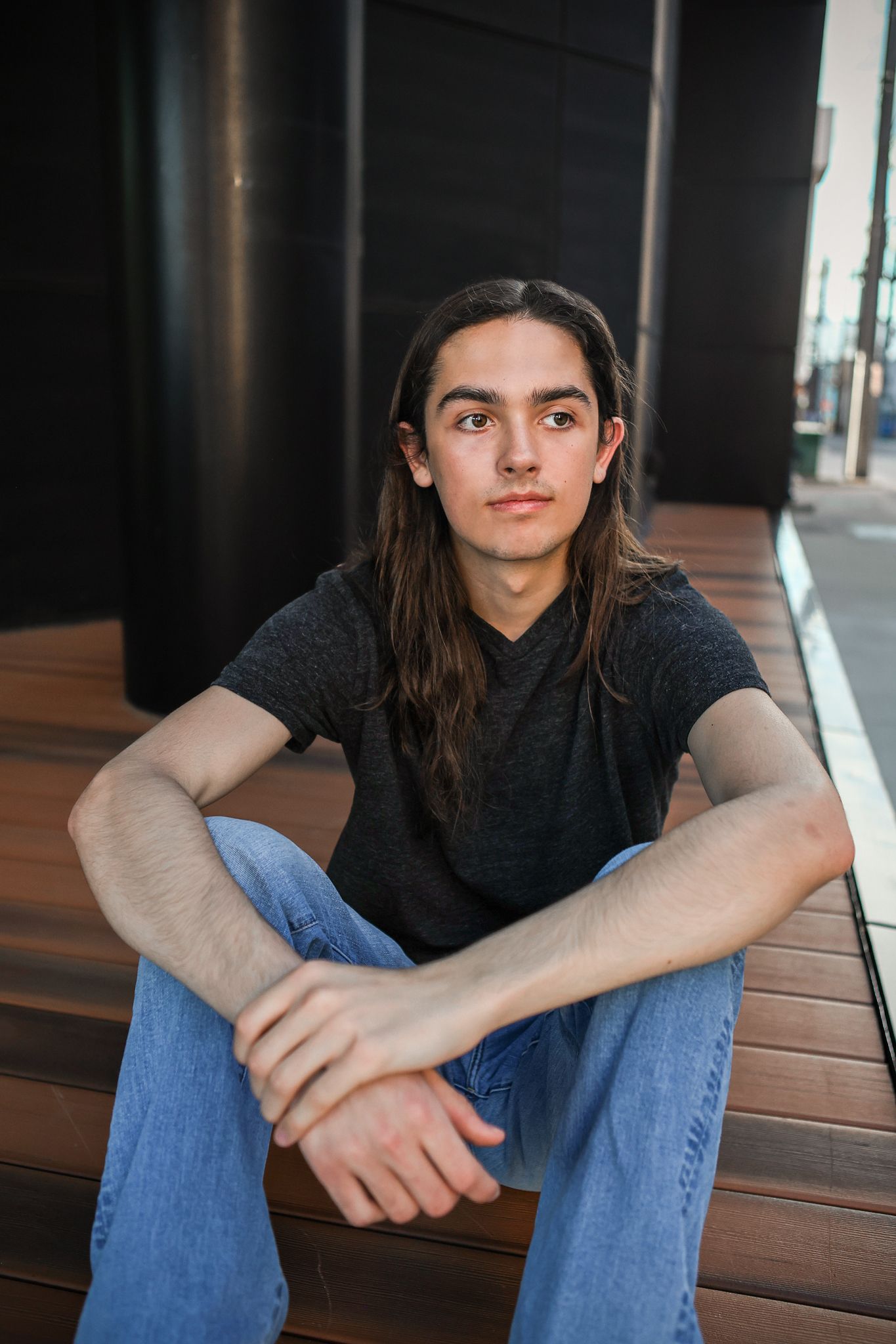 High School Senior boy wearing black tshirt and jeans sitting outside urban building in downtown Springfield MO