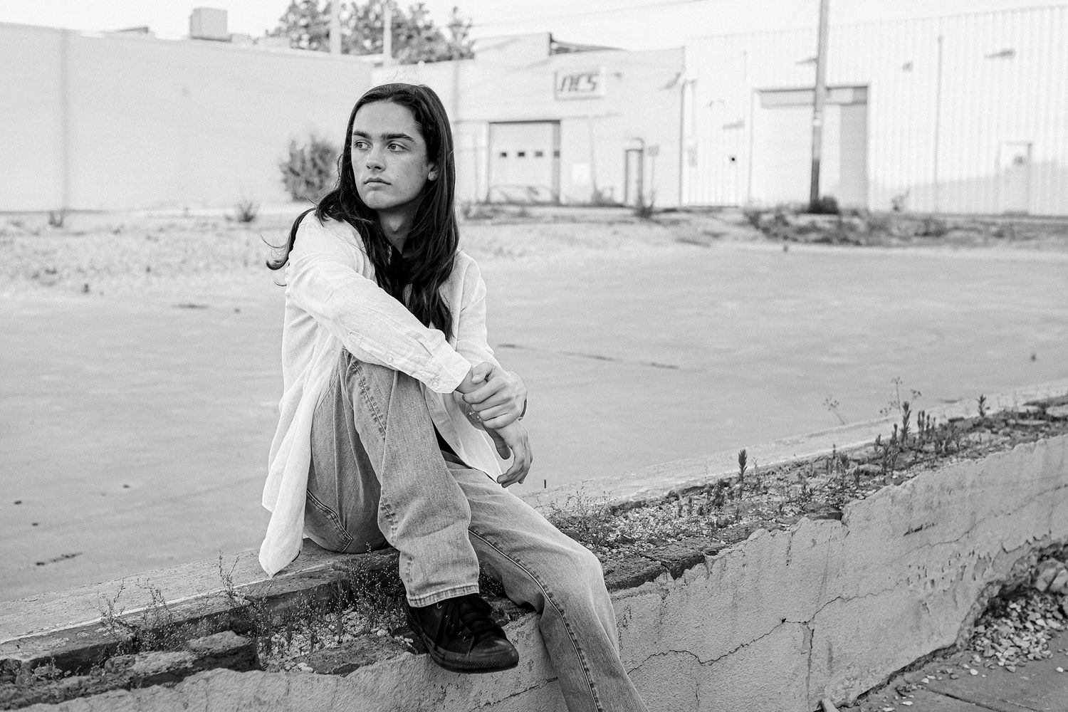 High School Senior boy sitting on brick wall  in urban setting in downtown Springfield MO.