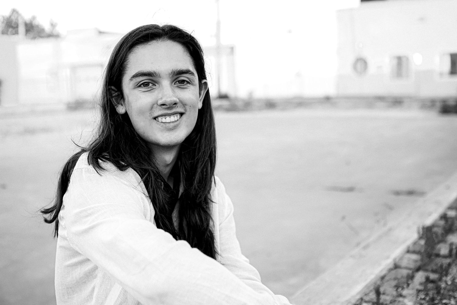 High School Senior boy sitting on brick wall  in urban setting in downtown Springfield MO.