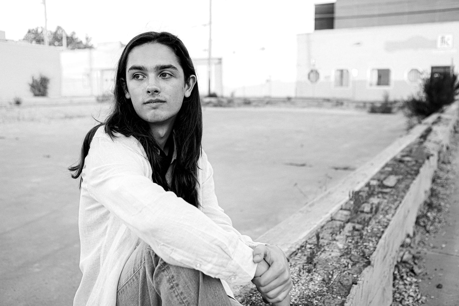 High School Senior boy sitting on brick wall  in urban setting in downtown Springfield MO.