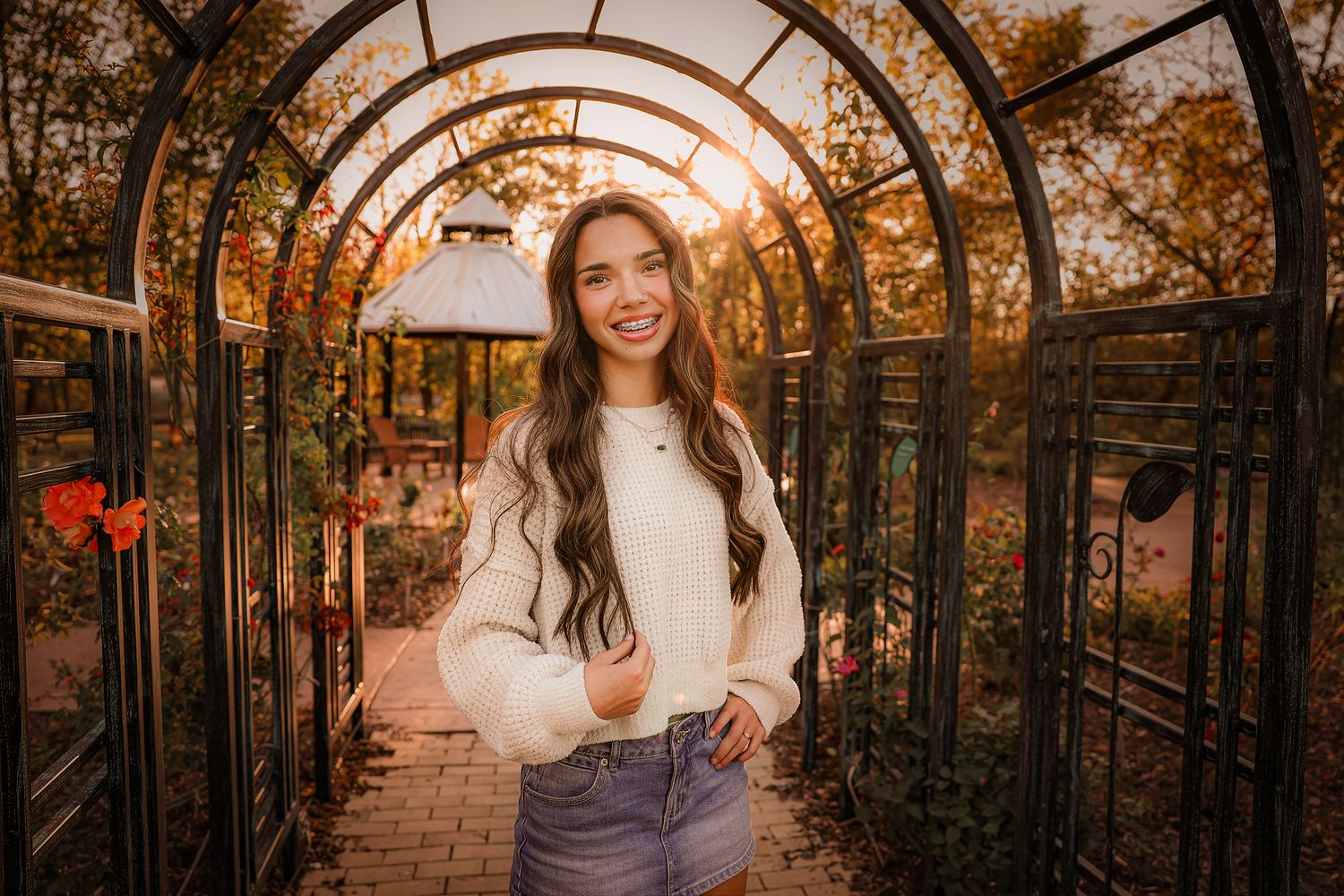 High school senior girl wearing white sweater under archway in Springfield MO