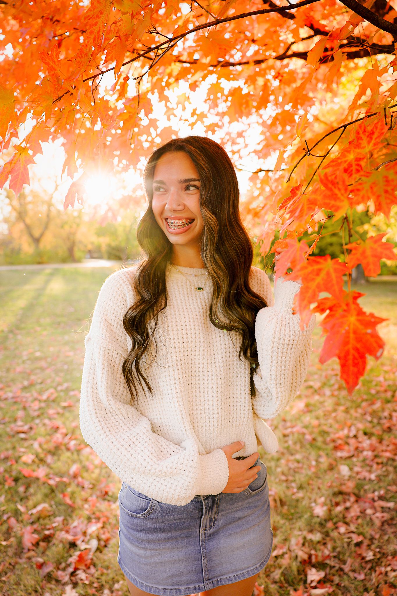 High school senior girl wearing white sweater under tree during fall golden hour in Springfield MO