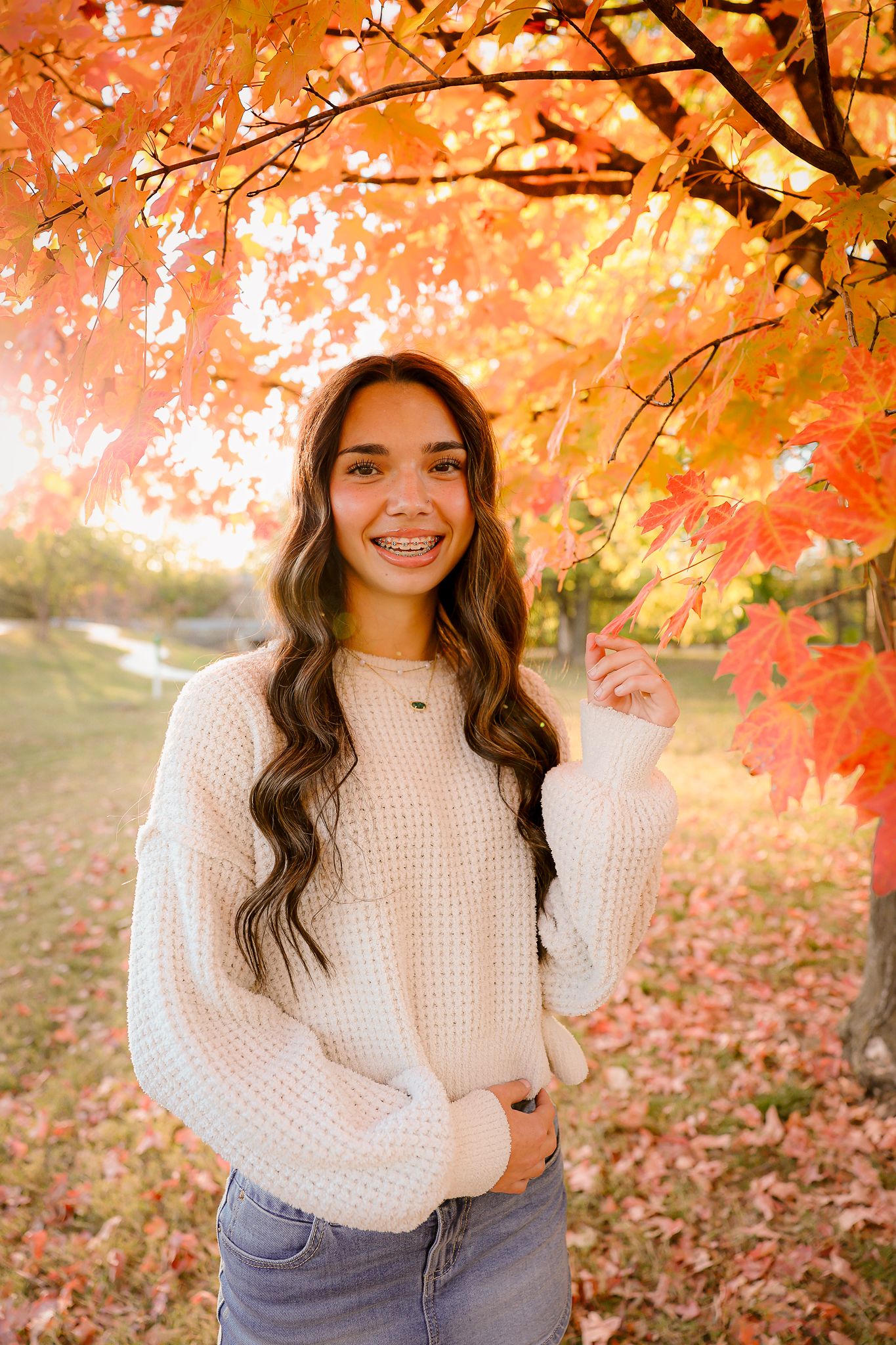 High school senior girl wearing white sweater under tree during fall golden hour in Springfield MO