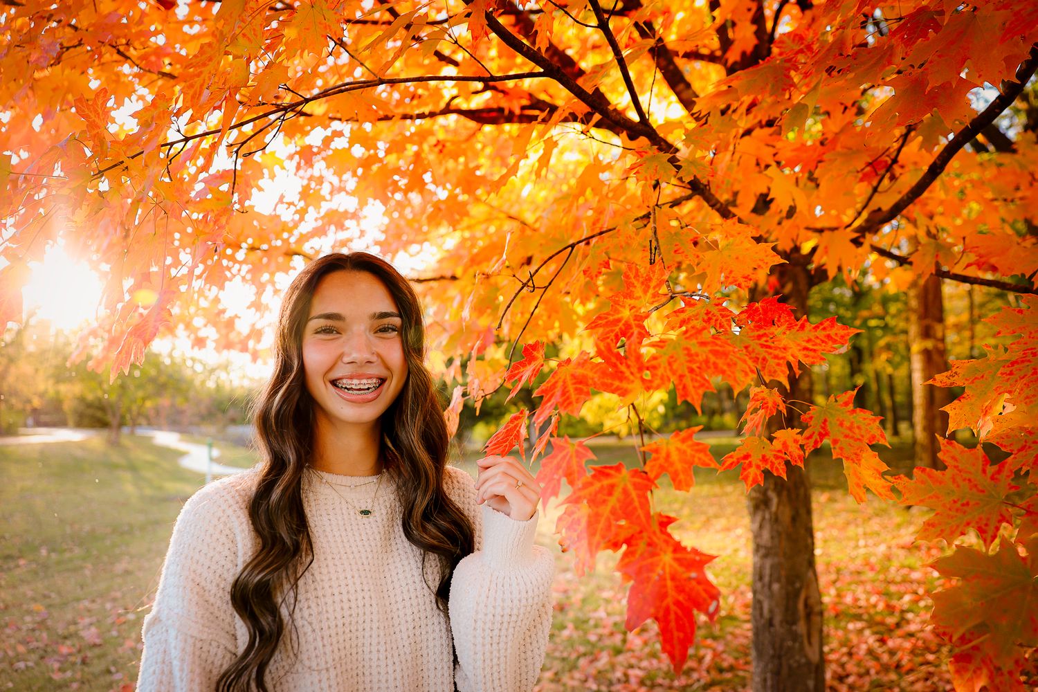 High school senior girl wearing white sweater under tree during fall golden hour in Springfield MO