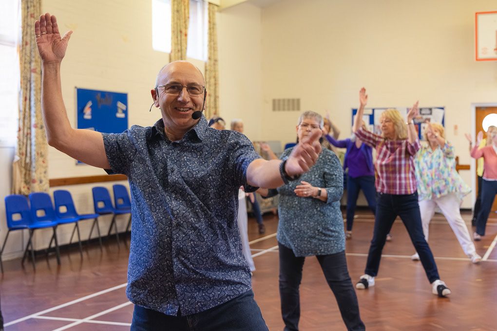 People participating in a dance or exercise class in a Letchworth Garden City community centre hall.