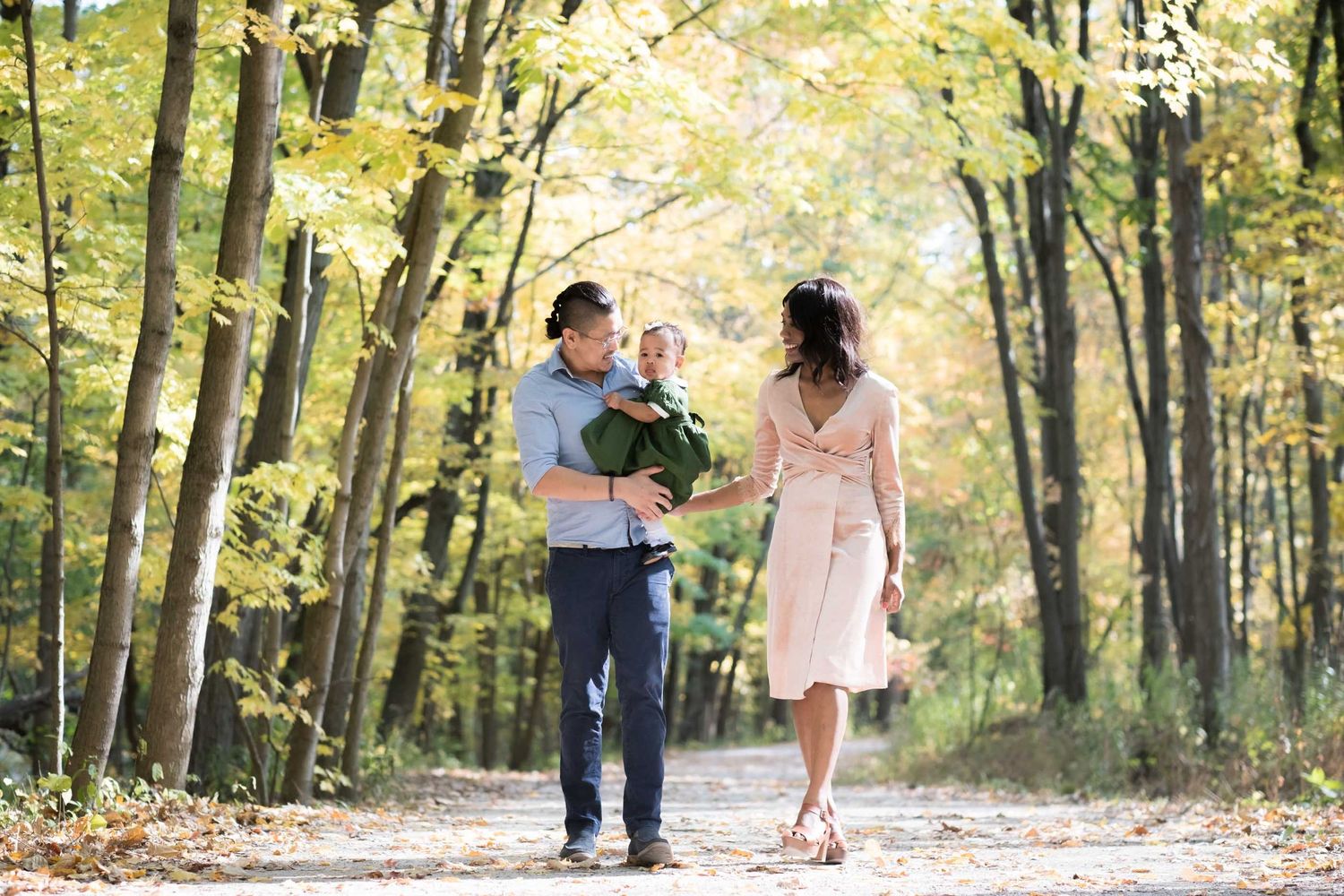 A family in casual attire shares joyful moments together outdoors on a sunny day.