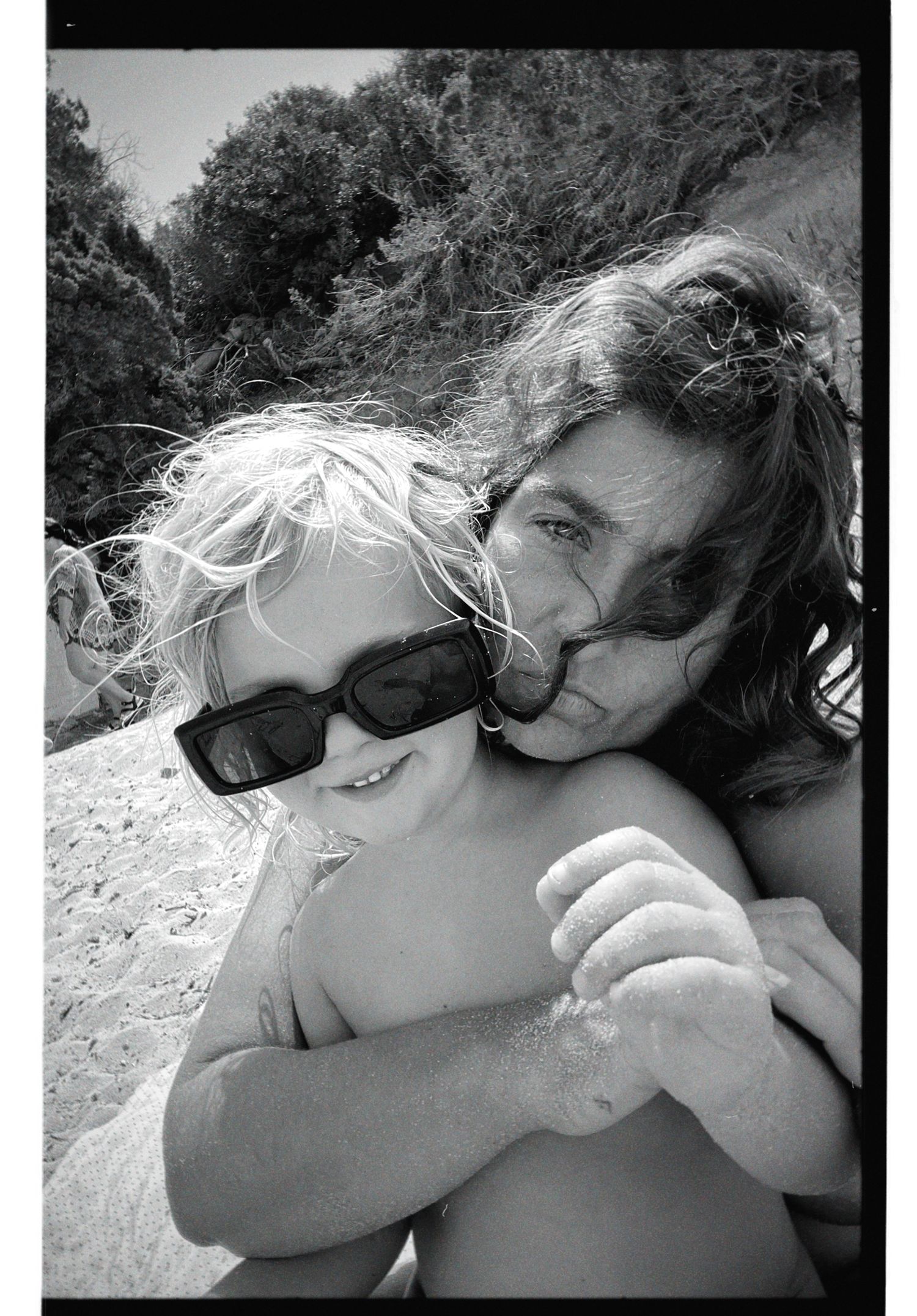 Black and white photos show someone cuddling and holding a small white dog outdoors in bright sunlight.