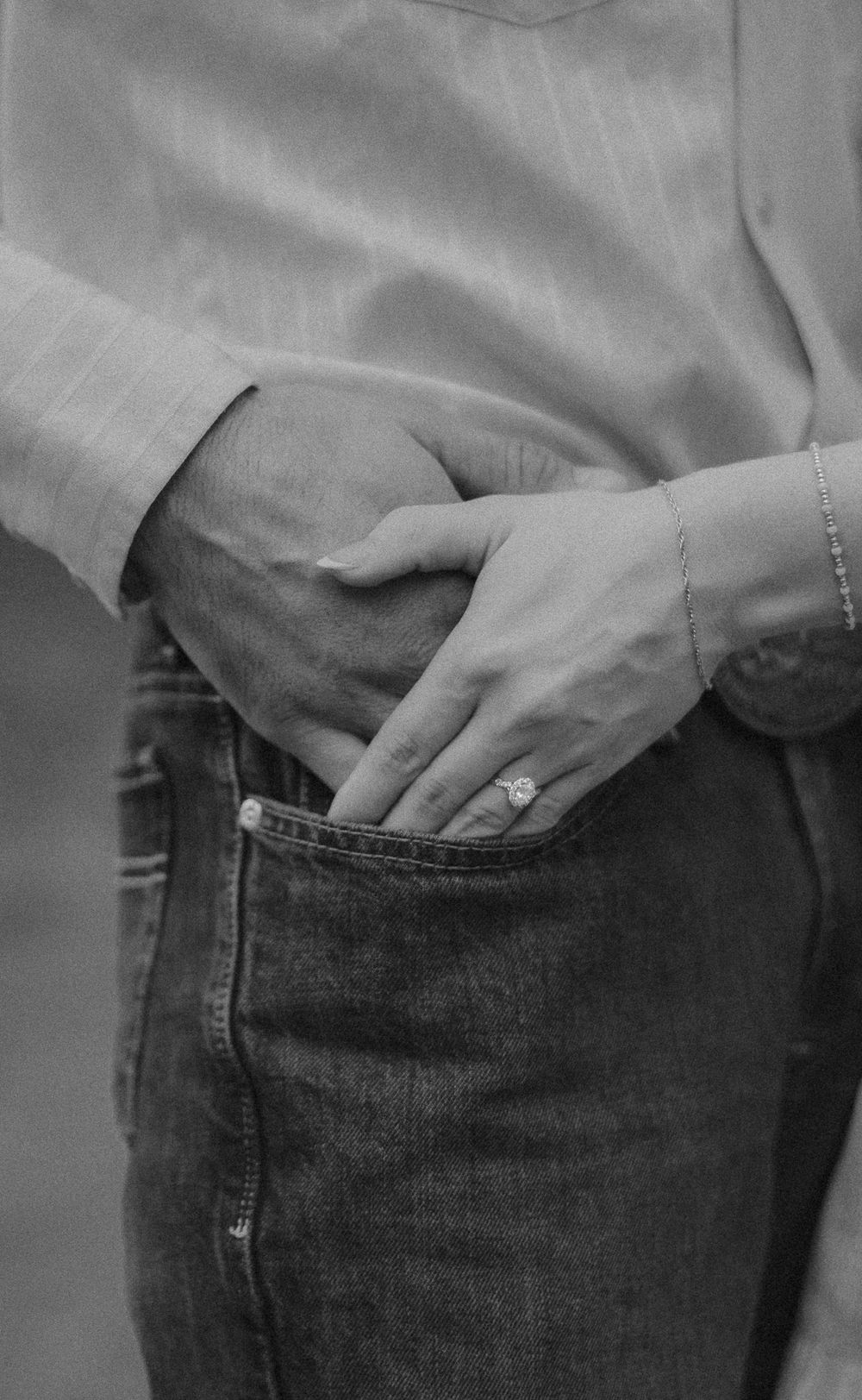 A person's hand slides into the front pocket of faded blue jeans in a black and white photograph.