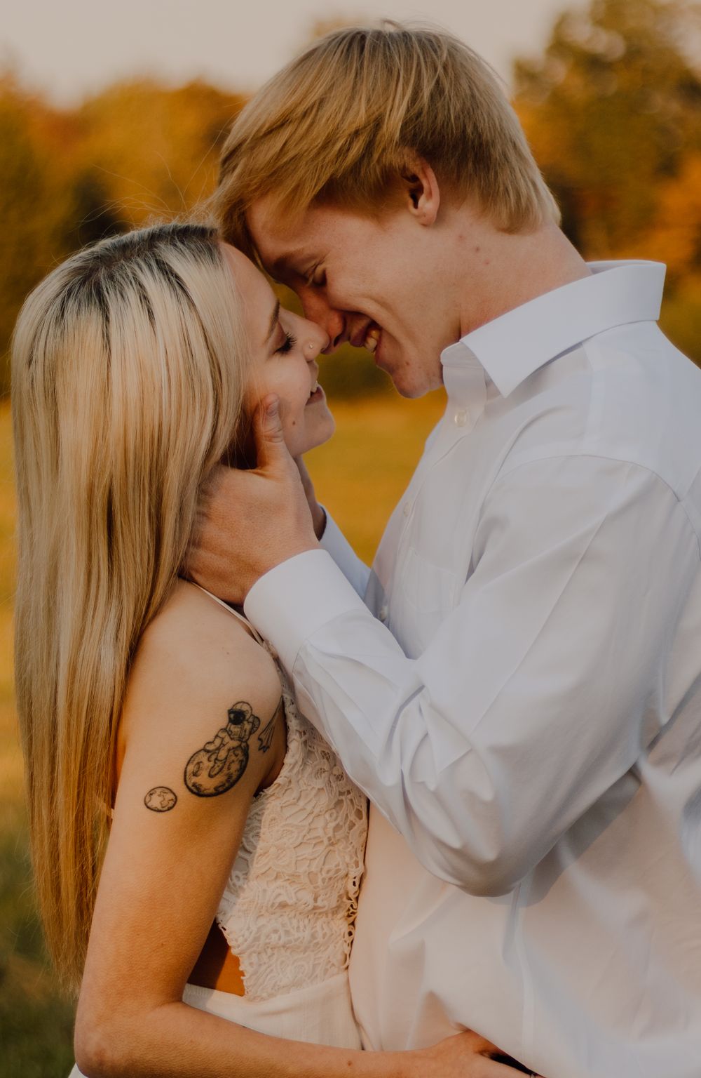 A romantic couple embraces in a golden autumn setting during a sunset photoshoot.