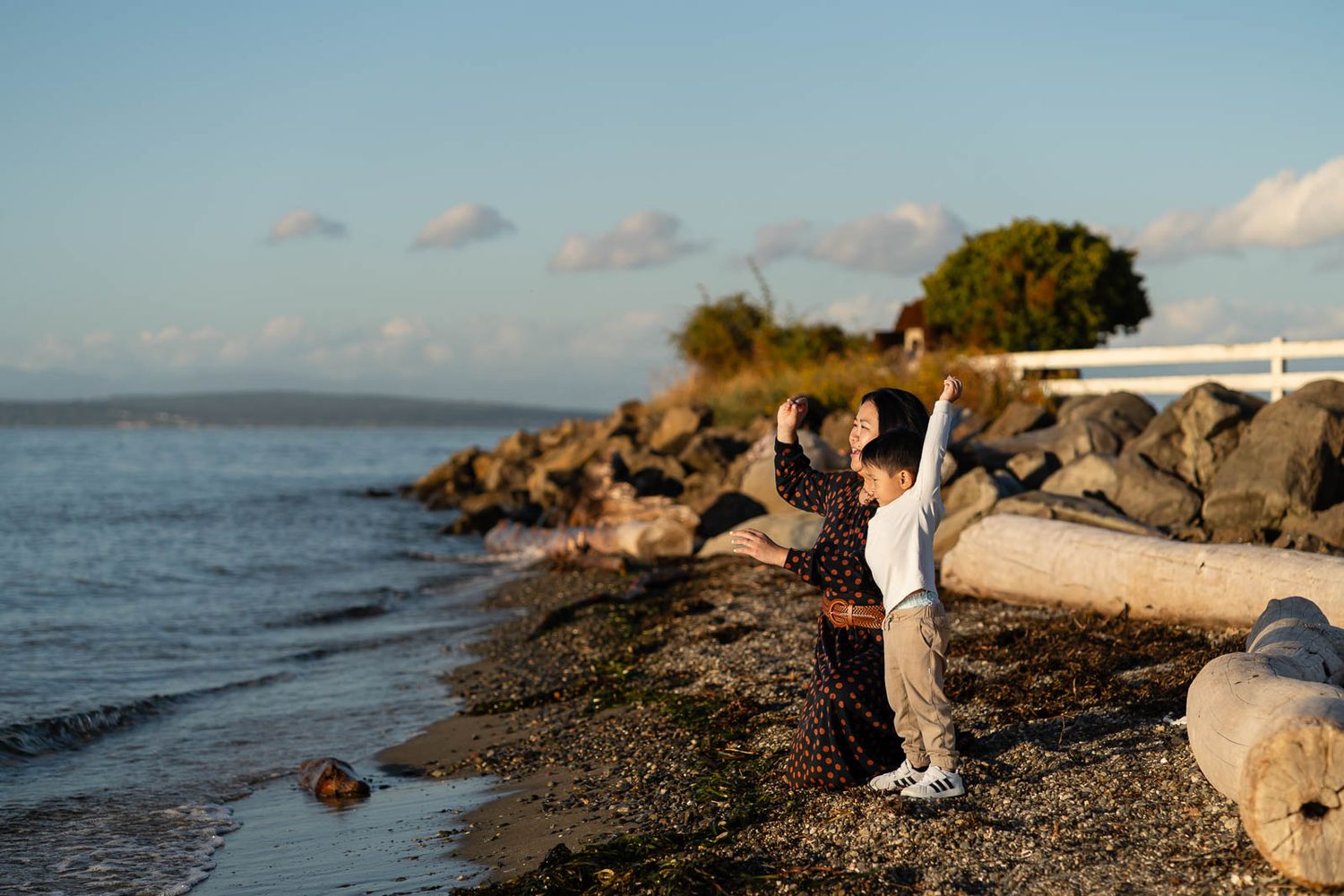 Mom and son throwing rocks by the beach.