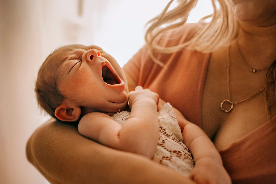 Mother holding newborn baby in soft natural light – Amber Potter Photography.