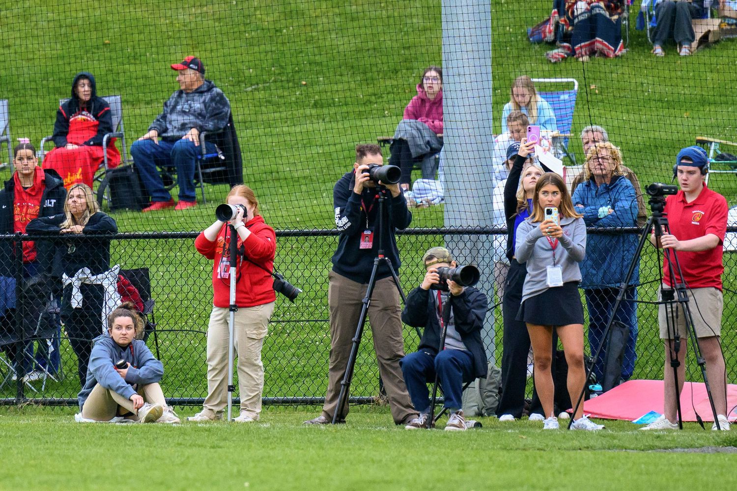 Campbell Mulligan and other photographers stand on the field during baseball game looking through camera