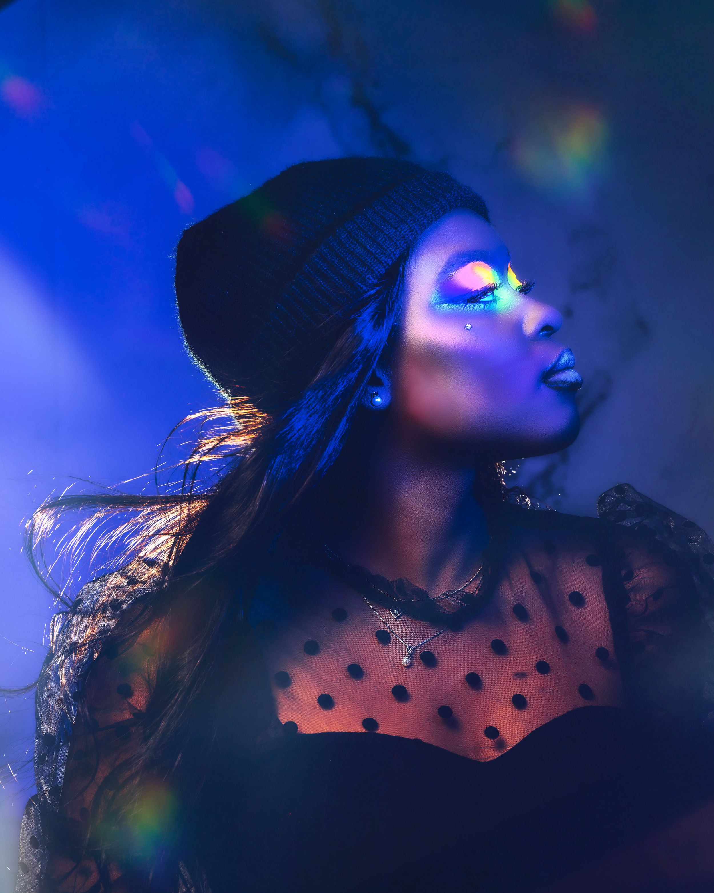 Artistic portrait with blue lighting and rainbow prism effects.
