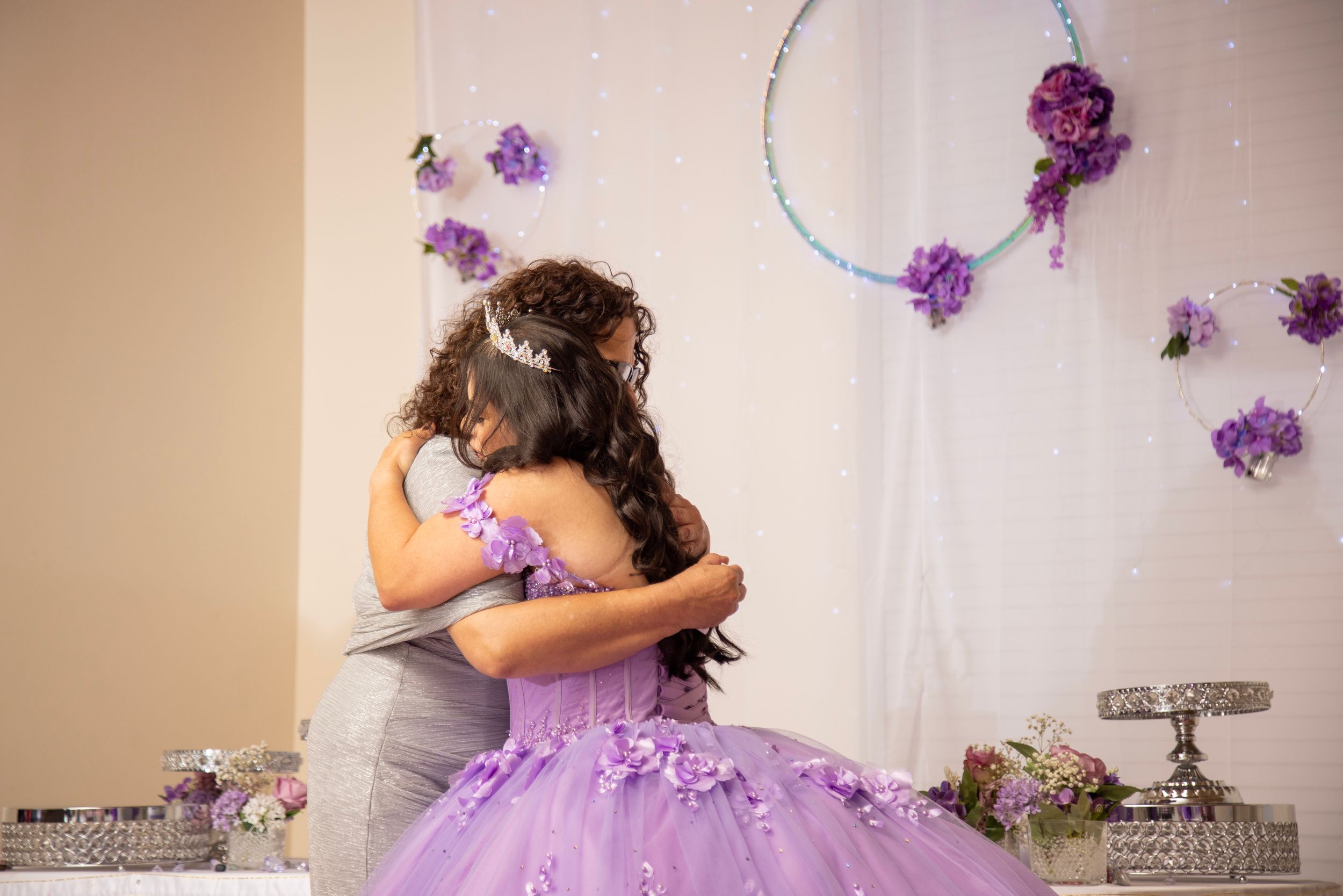 A purple floral dress twirls in a sunlit room creating a dreamy ethereal effect with scattered flower petals.