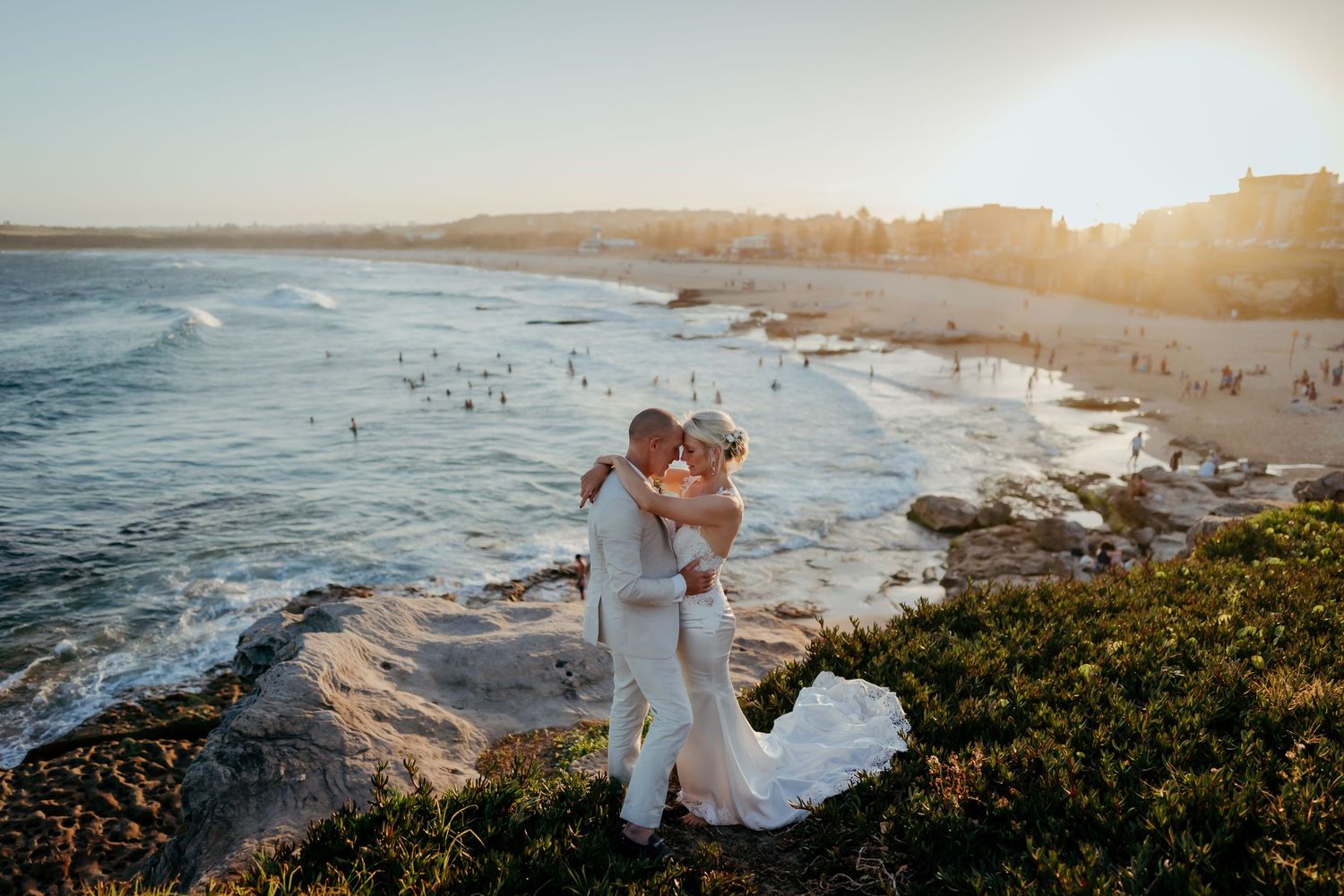 Stunning coastal wedding photos captured at sunset on a beach with crashing waves.