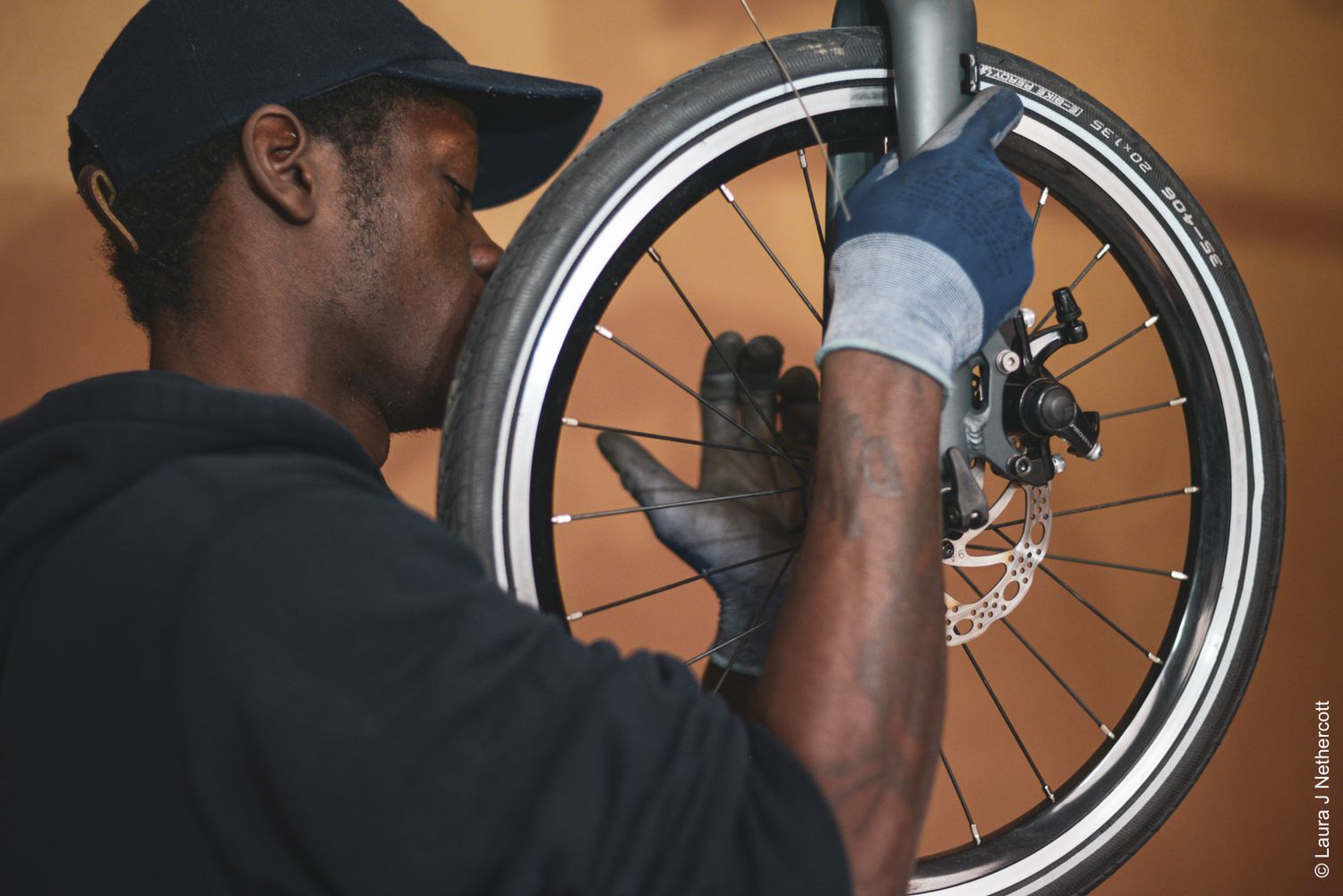Close-up of a bicycle wheel being serviced with disc brake maintenance against an orange background.