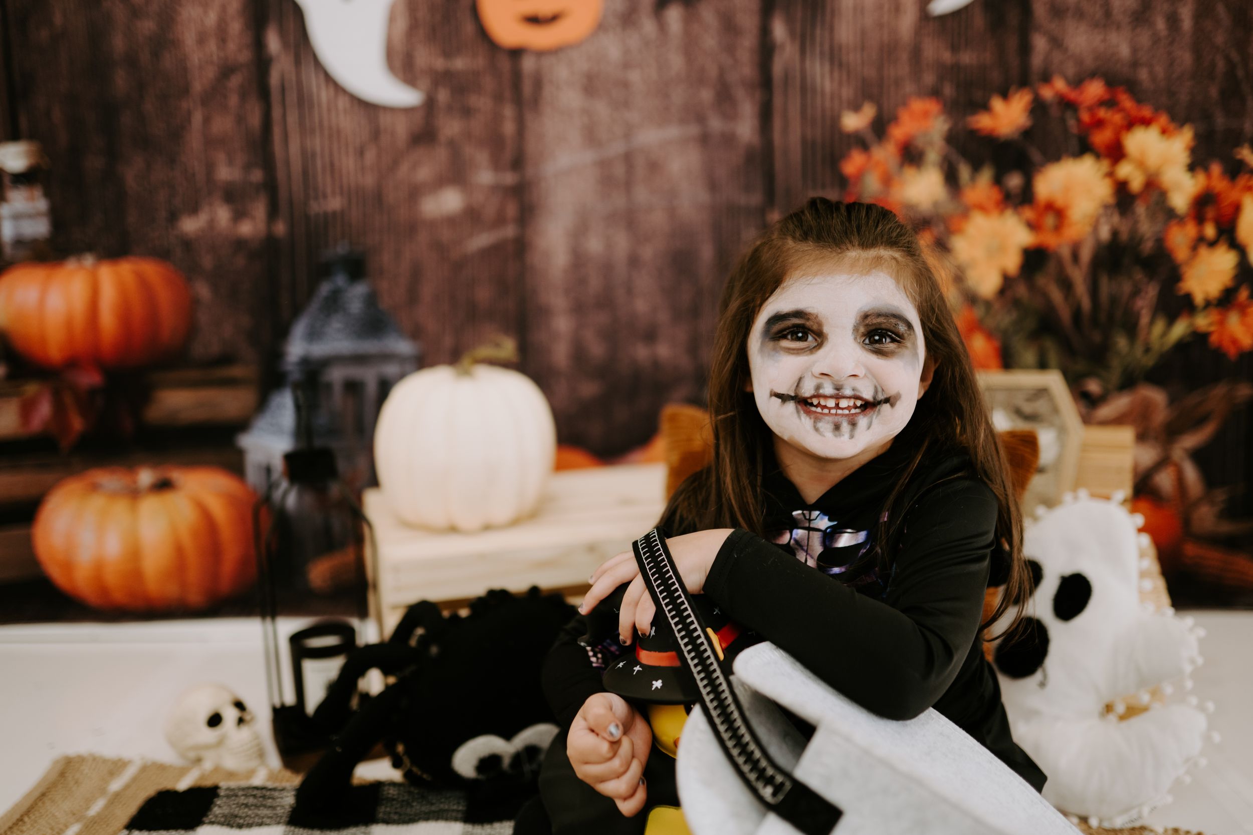 Festive Halloween setting with pumpkins, fall leaves, and skeleton costume.