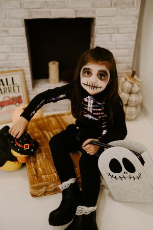 Cozy Halloween setup with skeleton costume and decorative Jack Skellington pillows.