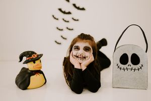 Halloween themed photo with flying bats and skeleton costume against neutral background.