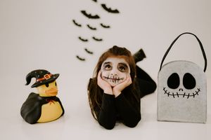 Minimalist Halloween scene with bats, skeleton costume, and decorative elements.