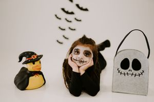 Halloween decorations including bats and spooky characters arranged in a minimalist row against a light background.