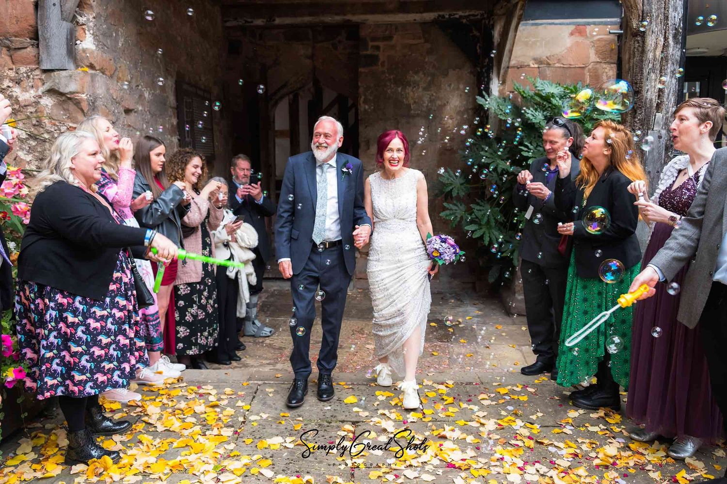 A cheylesmore manor wedding photographer captures a bride and groom bubble exit photo outside the ancient building.
