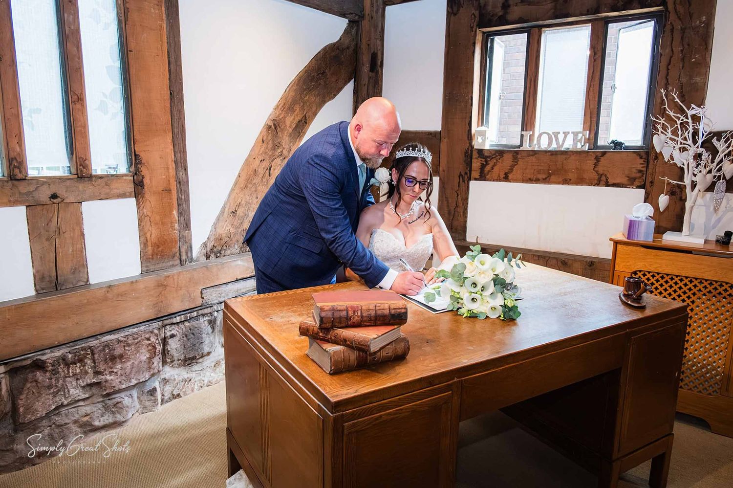 Cheylesmore Manor wedding photographer captures the bride and groom signing the marriage certificate in The Library Room