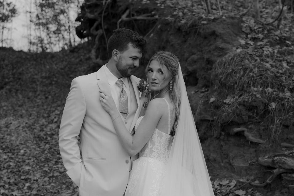 Bride and groom share an intimate black and white portrait moment outdoors.